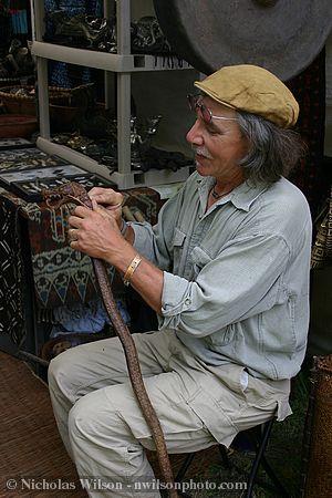 A vendor touches up a carved walking stick