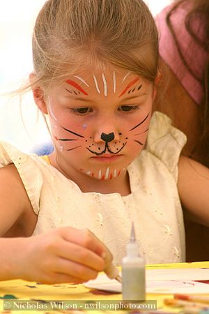 Girl with painted face doing silk hoop painting