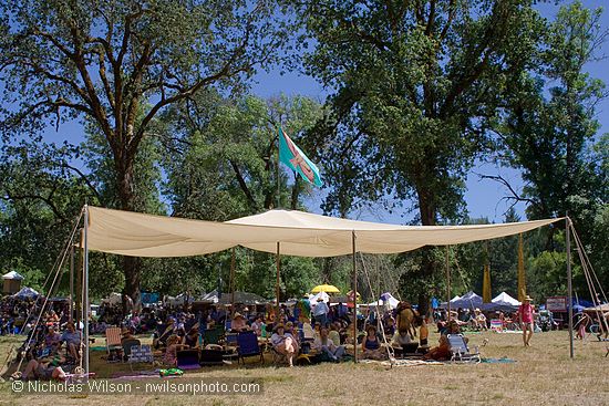 A large cargo parachute provides shade at the rear of the main concert bowl.