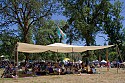 A large cargo parachute provides shade at the rear of the main concert bowl.