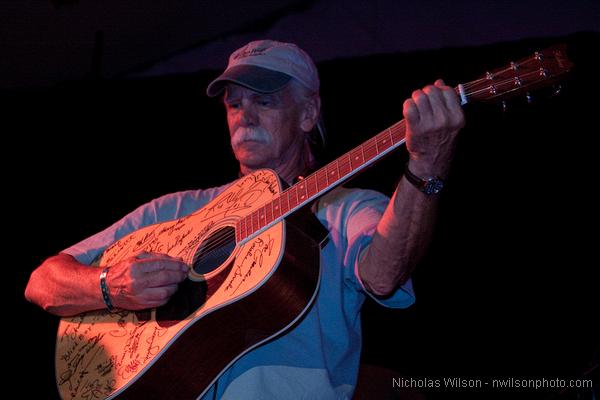 Stage manager Che Greenwood demonstates the autographed guitar which will be raffled off for charity.