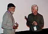 Les Blank holds the 2011 Maysles Award trophy as Bill Nichols applauds.