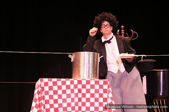 In a wonderful gag, Bill Irwin has stretched a very long piece of spaghetti around through the wings, across the back of the stage, and back to the cook pot in his performance at Cotton Auditorium, Fort Bragg CA