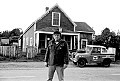 Byrd Baker, Mendocino sculptor and organizer of the Mendocino Whale War stands in front of his home, the red house on Ukiah St.  across from Corners of the Mouth food store in Mendocino. His classic Land Rover is painted with anti-whaling slogans such as "Stop the Slaughter" and "Boycott Japanese Products." Photo © 1976 Nicholas Wilson, PO Box 943, Mendocino CA 95460, negative  2/8/76-A25, scanned from 35mm neg at 2700 dpi, Nikon LS-2000.